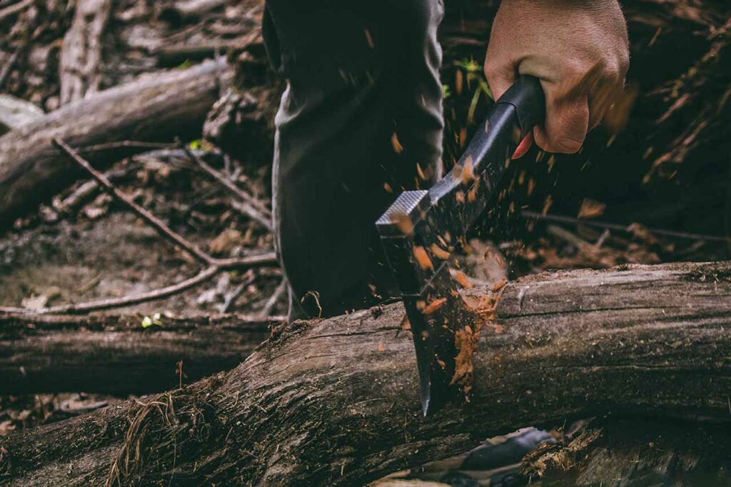 Ein Mann hackt mit der Survival-Axt Holz