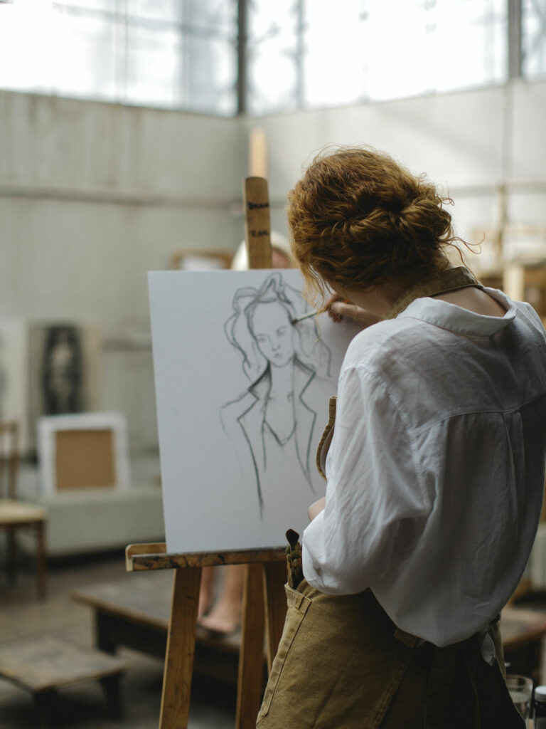 Eine junge Frau malt ein Bild auf einer Leinwand an der Staffelei