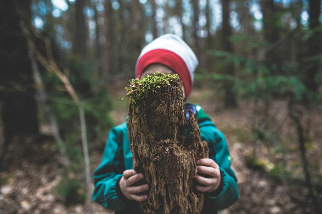 Ein Kind hält ein großes Stück Totholz vor sein Gesicht