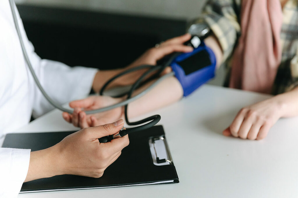 Eine Ärztin misst bei einem Patienten den Blutdruck