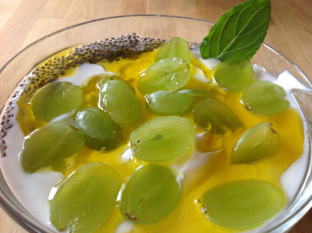 Leinöl und Leinsamen in Joghurt mit geschnittenen Weintrauben und einem Pfeffermintblatt garniert