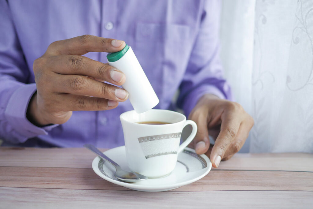 Ein Mann süßt seinen Kaffee mit einem Süßstoff, der Sucralose enthält