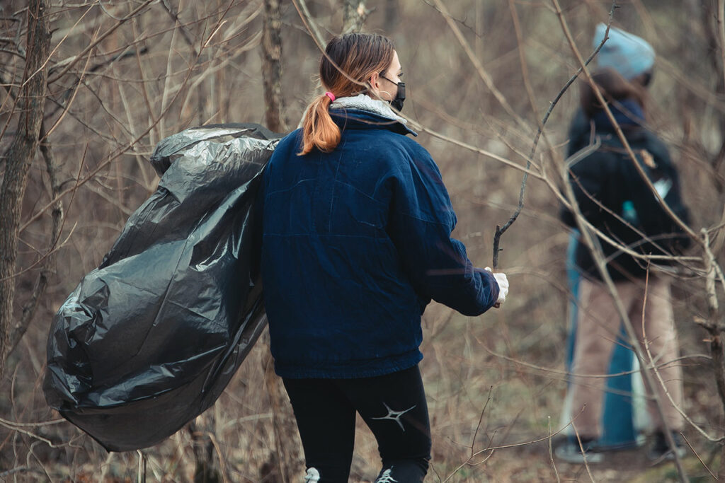 Ein Mädchen mit einem Müllsack sammelt Müll im Wald