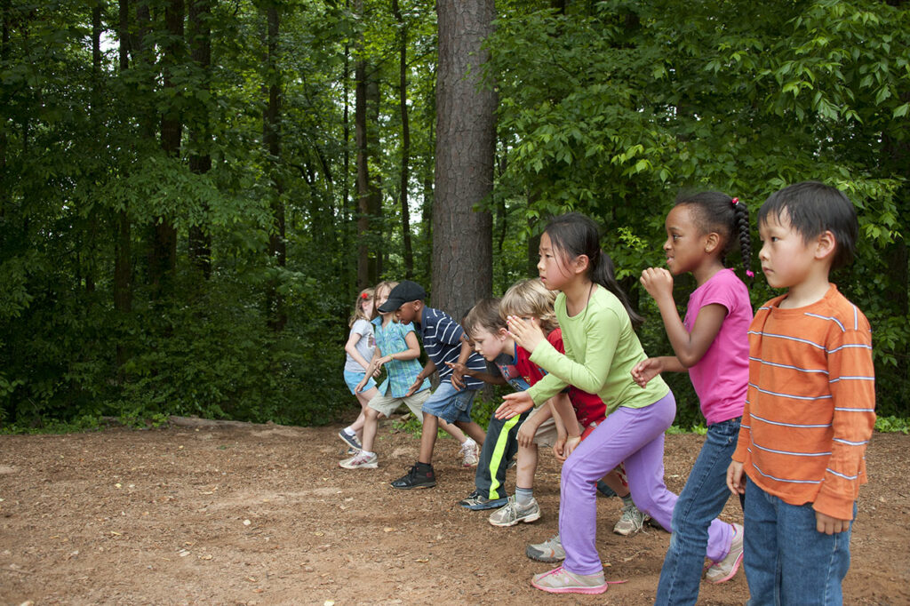 Mehrere Kinder stehen auf einem Waldweg in Reihe um zu einem Waldlauf zu starten